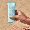 DUNE Suncare The Mineral Melt - Model shown dispensing product onto fingers