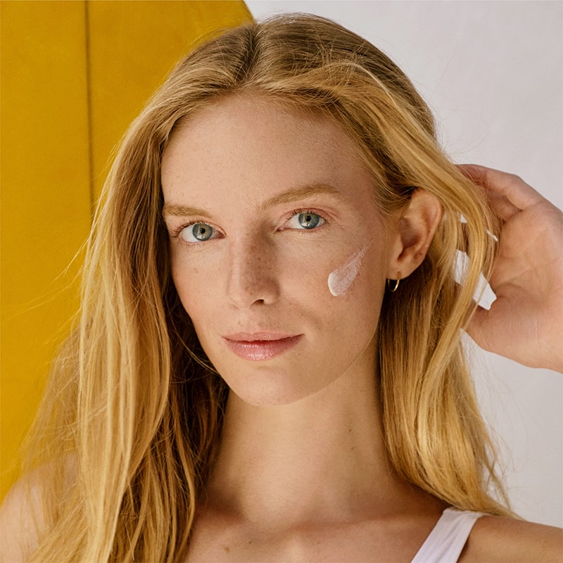 DUNE Suncare The Mineral Melt - Model shown with product streak on cheek