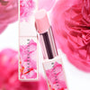 Close up of Chantecaille  Limited Edition Rose de Mai Radiant Lip Balm (2.5 g) with pink roses in the background