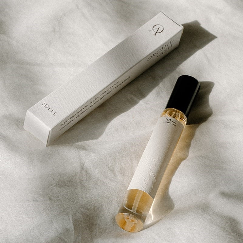 Orchid + Ash Idyll Perfume Travel Spray - Jasmine Incense + Vanilla - bottle and packaging shown on top of cloth