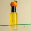 Orchid + Ash Daydream All-Natural Body Oil - Orange + Neroli - product shown with orange and oil dripping onto glass surface