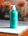 Kerzon Liquid Body Soap - Menthe Poivrée - Product shown on table in front of glass and flowers