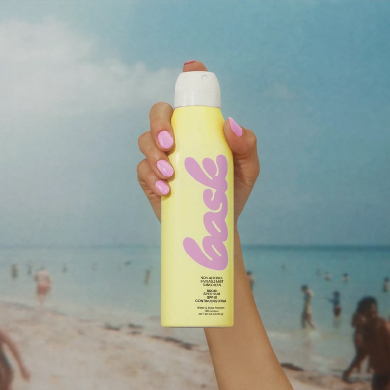 Bask Sunscreen SPF 50 Non-Aerosol Spray Sunscreen - model holding product on beach