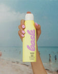 Bask Sunscreen SPF 50 Non-Aerosol Spray Sunscreen - model holding product on beach
