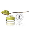 Kure Bazaar Matcha Lip & Nail Balm - product shown next to cap and spoonful of matcha powder on top