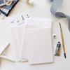 Emily Lex Studio Seaside Paintable Notecards - product shown stacked on each other next to paint brush, tube, ribbon, and starfish