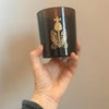 The Quiet Botanist In The Weeds Scented Candle - model holding product shown
