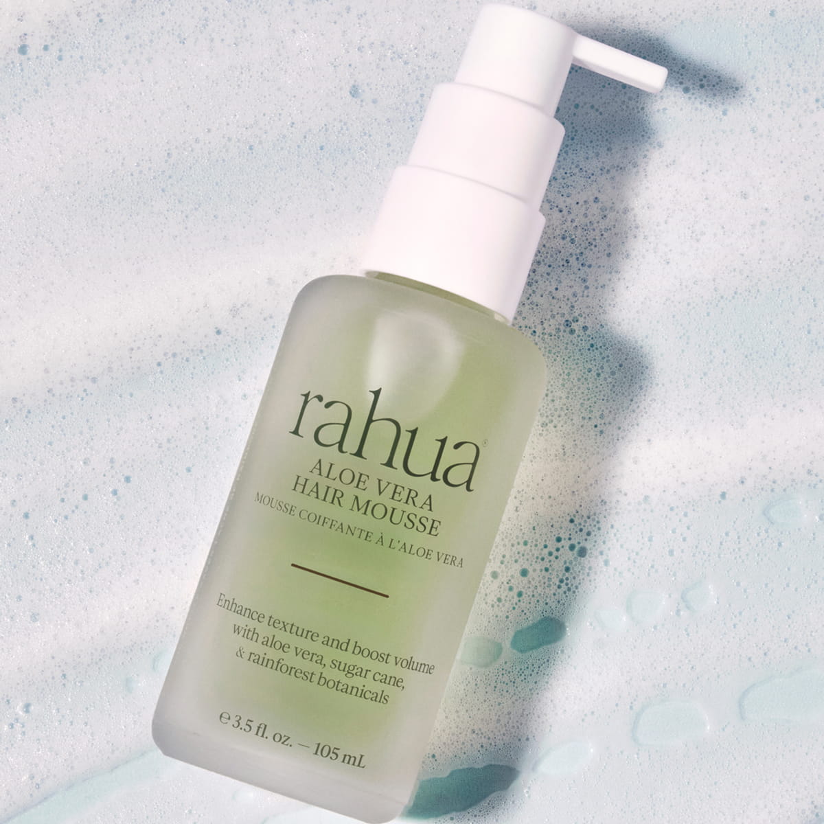 A bottle of Rahua Aloe Vera Hair Mousse (105 ml) with foamy mousse in the background