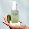 A bottle of Rahua Aloe Vera Hair Mousse (105 ml) is held in a hand with foam mousse in the palm of the hand alongside a sliced aloe vera leaf
