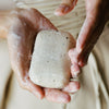 Close up of Activist A.M.S Manuka Botanical Soap Bar (4.23 oz) shown in hands with slight later