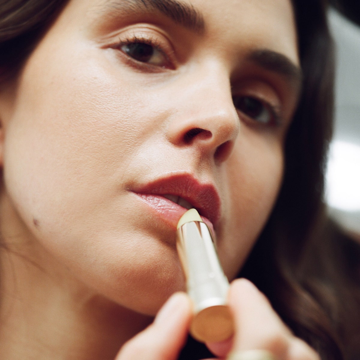 Activist A.M.S Manuka Honey Lip Balm (0.13 oz)- product shown being applied by model. 