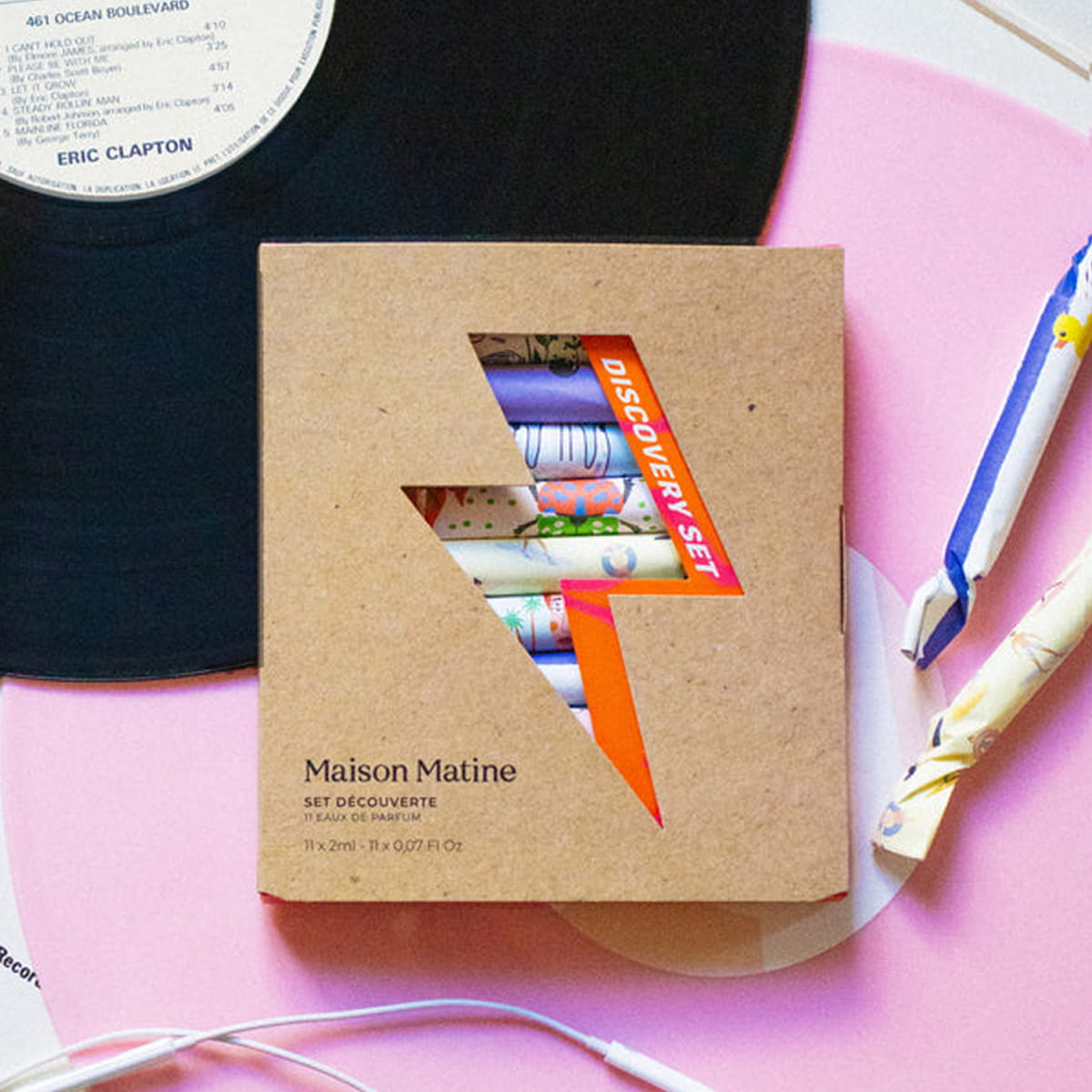 Maison Matine Discovery Set (11 x 2 ml), styled on a pink surface with a black vinyl record, earphones, in the background