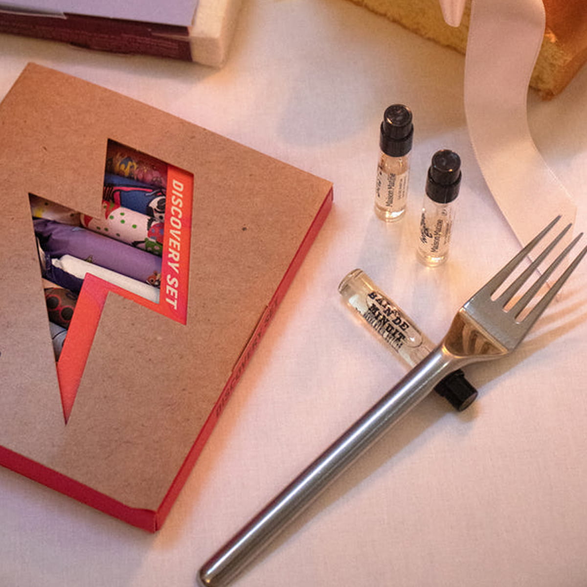 Maison Matine Discovery Set (11 x 2 ml) on a light surface, with three small vials shown, and a silver metal fork resting on the surface.