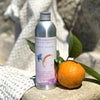 La Selva Positano Orange and Lavender Aromatherapy Cleanser - product shown next to orange sitting on rock with towel 