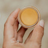 Smithereen Farm Bixa Fixa Healing Salve - model holding opened product showing texture and color