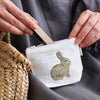 Lifestyle shot, close up of model placing lipstick in Fog Linen Work Isabelle Boinot Pouch - Rabbit and Carrot