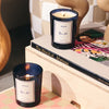 ROEN Candles Rue 52 Scented Candle - two lit products on top of books