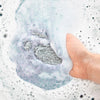 Bathorium Midnight Superbloom Crush Bath Soak - model hown with hand in bath with product