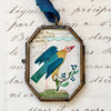 Maris Mirum Small Locket - Cassis Folk Bird - product shown on decorative paper