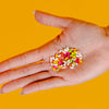 Paro Candied Fennel Seeds (15 g) - product shown being held by hand on orange background. 