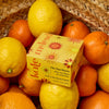 Kate McLeod Sun Stone After Sun Balm & Lotion Bar (3.5 oz) - product shown in basket with oranges and lemons. 