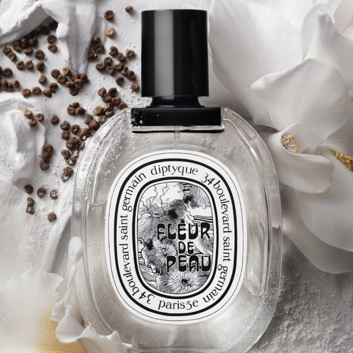 Close up of Diptyque Fleur de Peau Eau De Toilette (50 ml) - product shown next to flowers and beans. 
