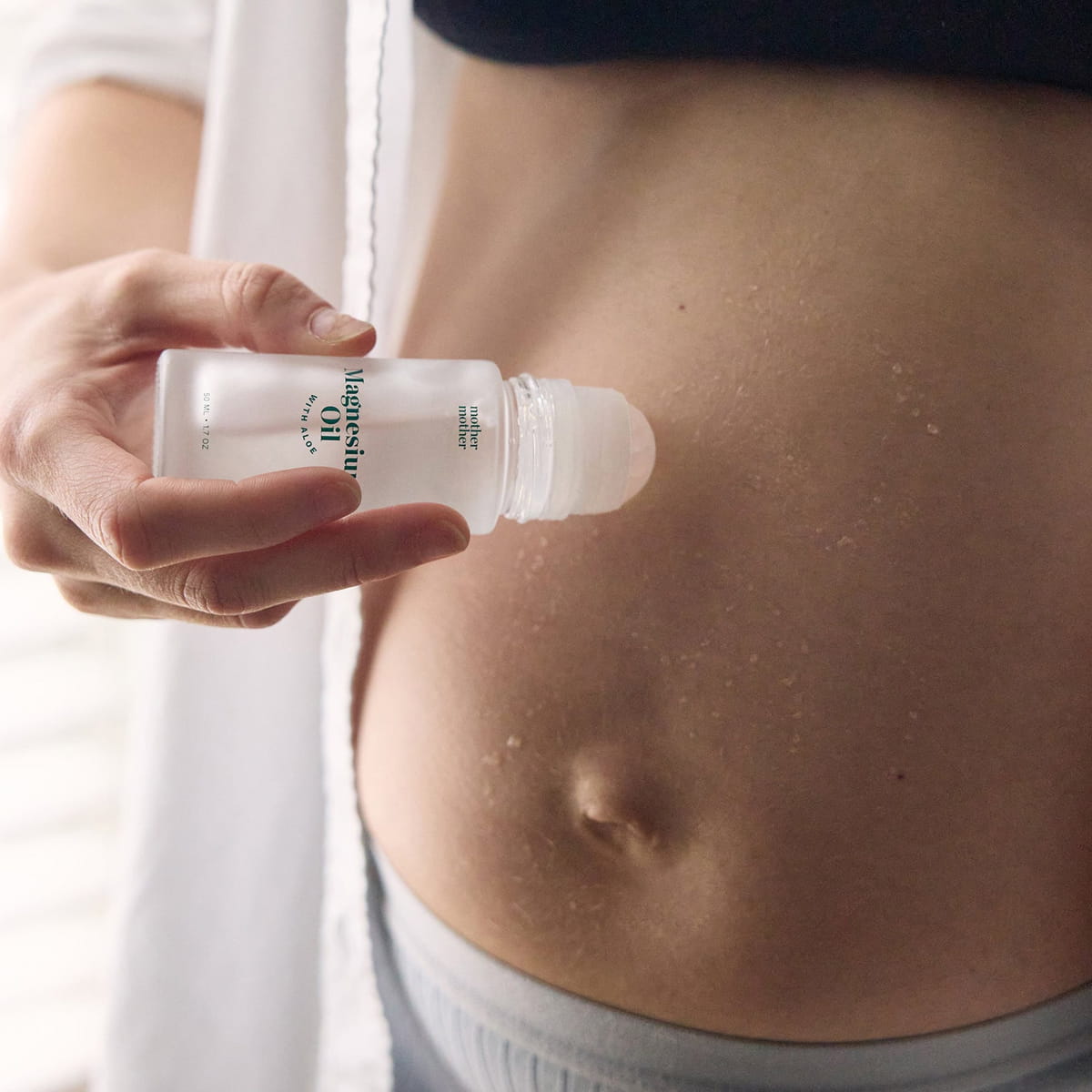 Mother Mother Magnesium Oil + Aloe Roller (1.7 oz) - product shown being applied to belly. 