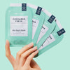 Hand holding VOESH New York Pedi in A Box - Cucumber Fresh (4 pcs - individual packets) against a light blue background
