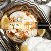 NETTE Lemon Puff Eau De Parfum Travel Spray (10 ml) on a decorative silver platter with lemon slices and whipped cream.