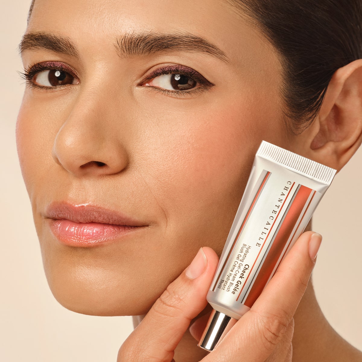 Up close shot of model wearing Chantecaille Cheek Gelee - Thrill and showing tube
