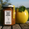Puckett’s Pickles Spiced Apple Chutney (226 g) bottle shown next to a yellow apple with leaves on wood slats