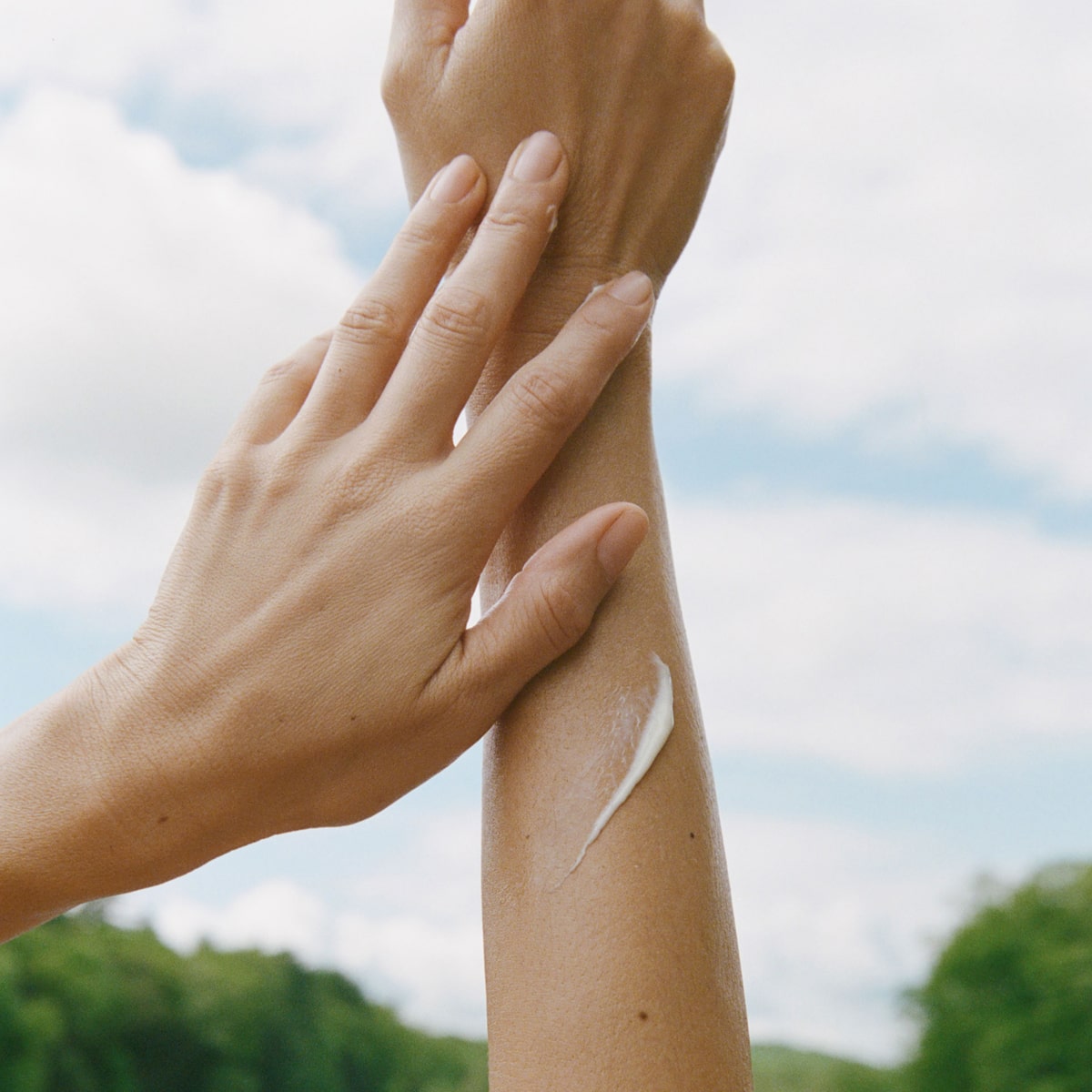 Ursa Major Golden Hour Body Serum - product shown with hands and product smear on arm