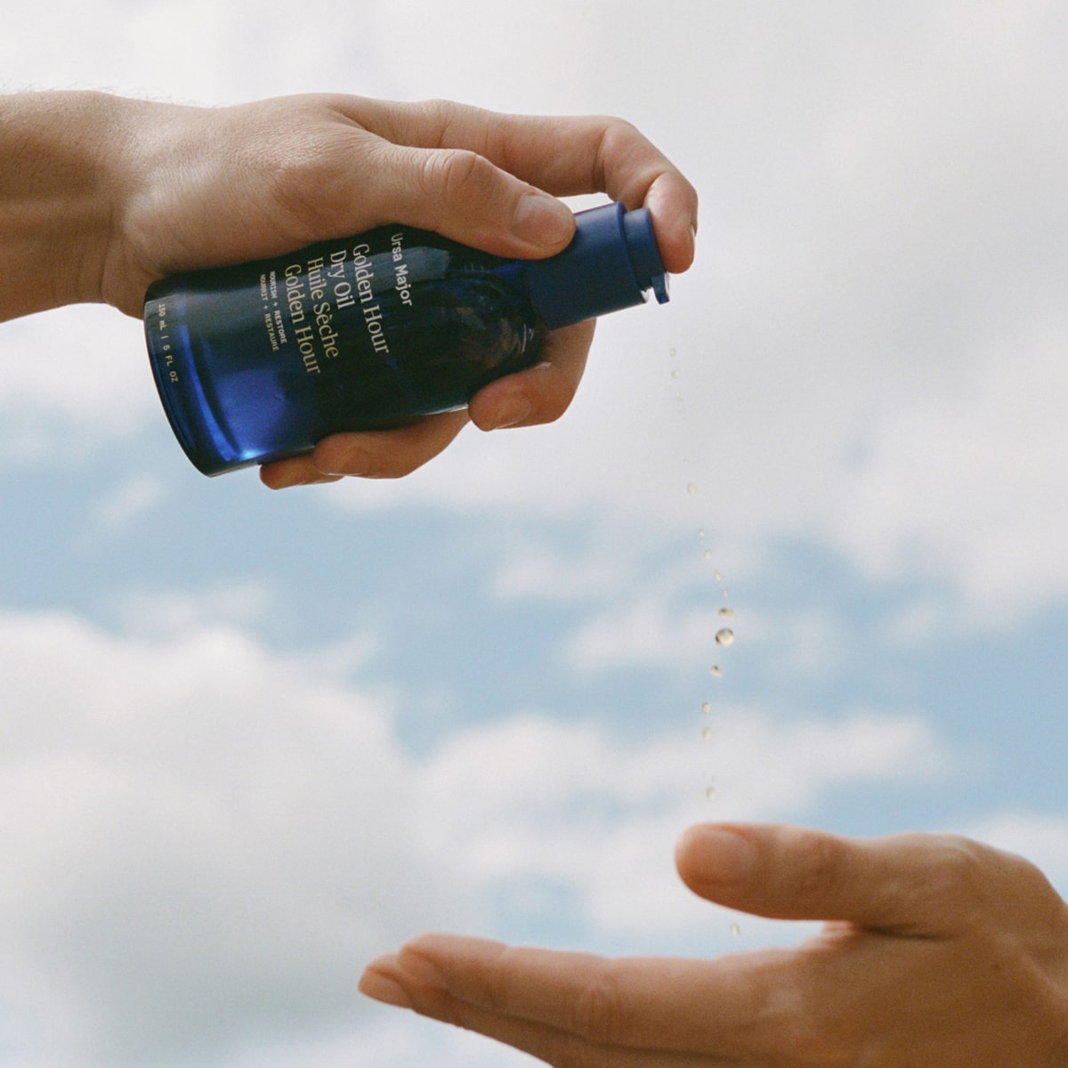 Ursa Major Golden Hour Dry Oil - product shown in hand pressing bottle pump 