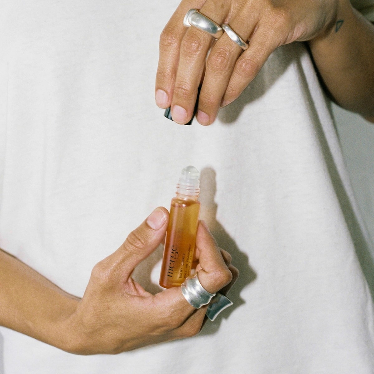 Merge Balmy Summer Roll-On Perfume Oil - product shown in models hands with cap off