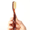 Close up of  model holding C.O. Bigelow Natural Bristle Toothbrush - Soft Tortoise (1 pc)