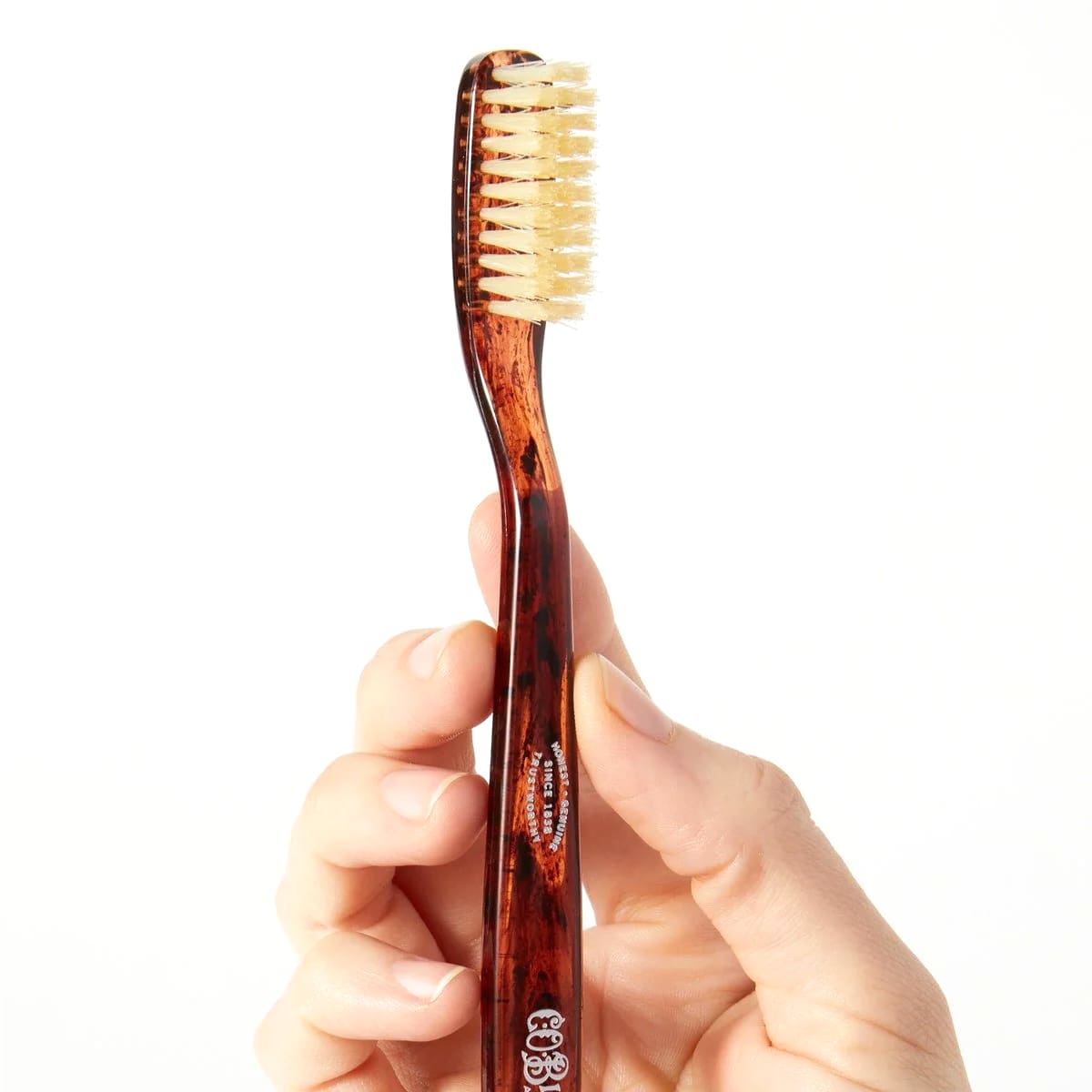 Close up of  model holding C.O. Bigelow Natural Bristle Toothbrush - Soft Tortoise (1 pc)