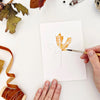 Emily Lex Studio Fall Leaves Paintable Notecards - product shown with paint brush and hands