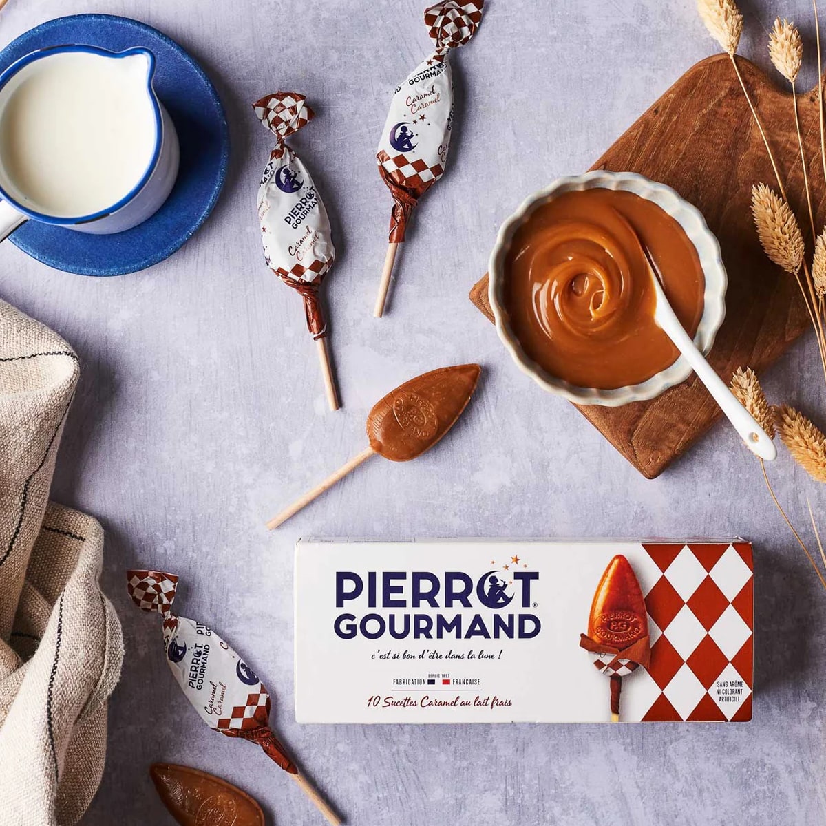 Pierrot Gourmand Milk Caramel Lollipops Box (10 pcs) - packaging shown next to a bowl of caramel and a mug 