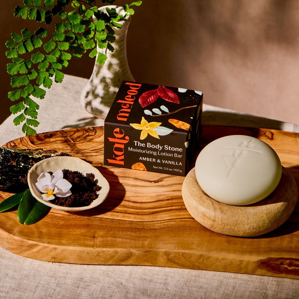 Kate McLeod Amber Vanilla Stone Deep Moisturizing Lotion Bar (3.5 oz) - Product shown on wood board with flowers. 