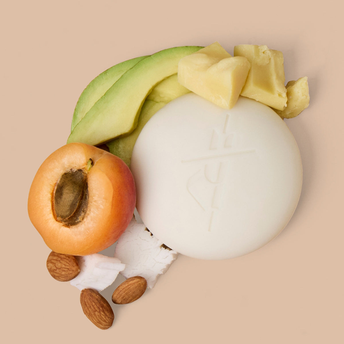 Avocado, Kate McLeod Oud Tuberose Stone Deep Moisturizing Lotion Bar (3.5 oz), apricot, and almonds arranged on a beige background