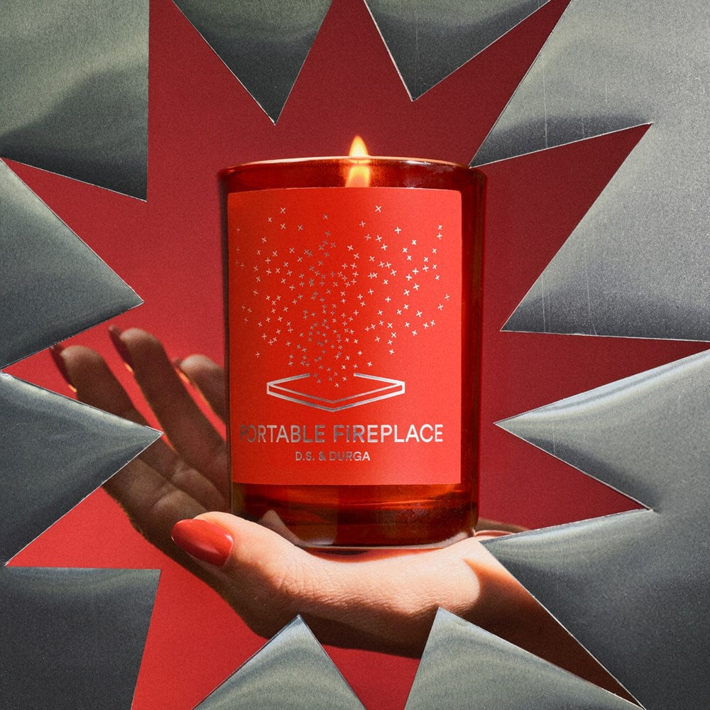 D.S. & Durga Portable Fireplace candle (7 oz)  - hand holding product in star cardboard cutout. 