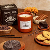 Nopalera Chocolate Ibarra Candle (8.5 oz) on a table with cookies, chocolate, cinnamon and vanilla beans.