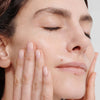 Close up of model applying Dr. Hauschka Regenerating Rhythmic Treatment to face