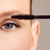 Close up of model applying Dr. Hauschka Long Lasting Mascara - Brown 02 to eyelash