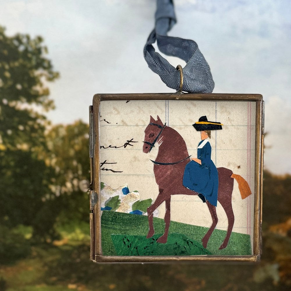 Maris Mirum Small Locket - Riding Day (1 pc) on a blurred natural background showing trees and sky
