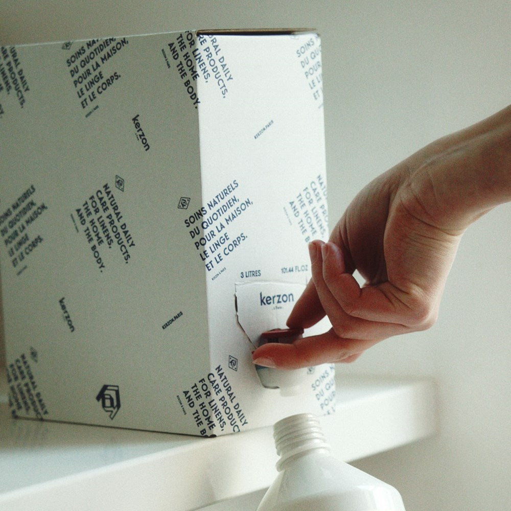 Lifestyle shot of person refilling bottle from Kerzon Laundry Soap Refill - Giga Doux (3 L)