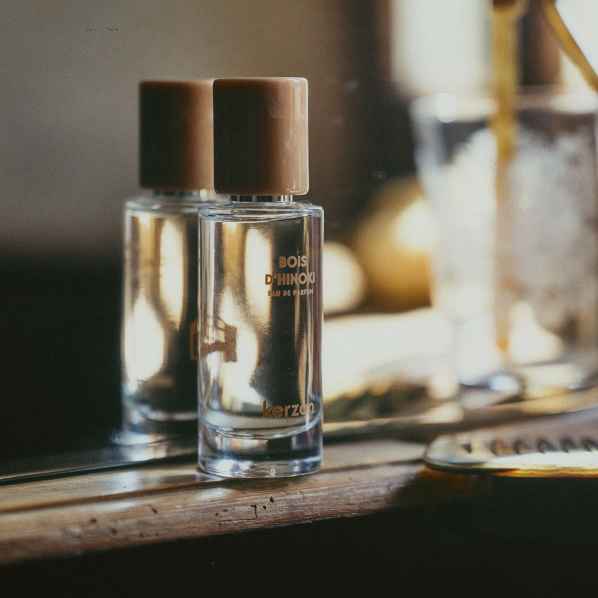Lifestyle shot of Kerzon Eau de Parfum - Bois D’Hinoki (50 ml) sitting on wood ledge with mirror behind bottle