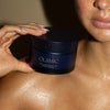 Olamic Retin-Algae Body Butter (6.7 oz) - model holding product near collarbone. 
