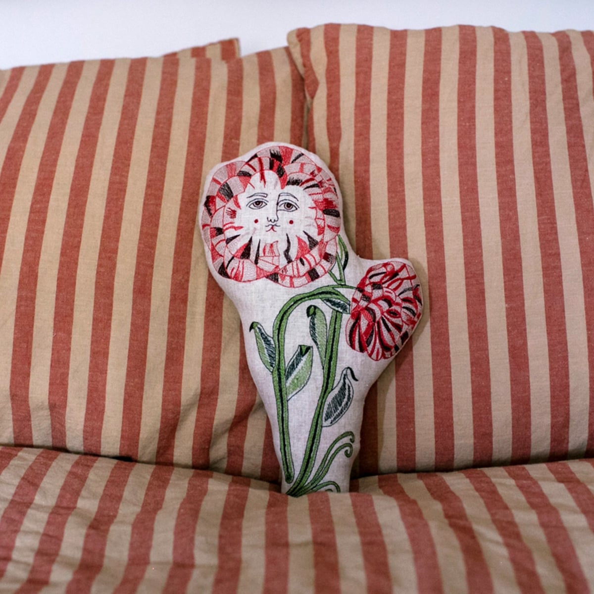 Skippy Cotton Poppies Pillow (1 pc) shown on red striped couch