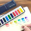 Breathe People Watercolor Paint Set with person creating colorful swatches on paper on a wood table